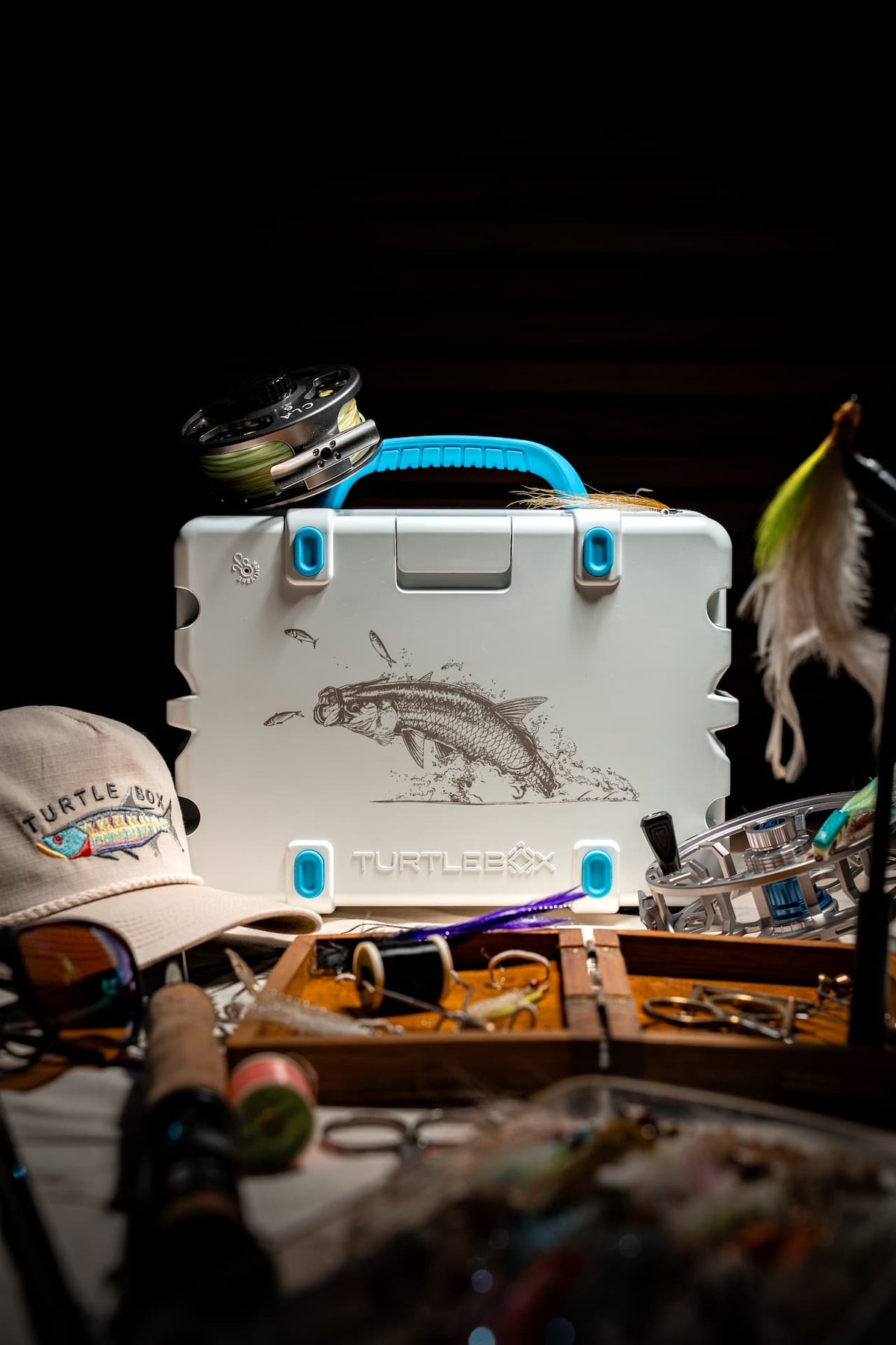 A lifestyle photo of the Turtlebox Fish Artist Series edition with hat and fishing material on the scenario #speaker-color_tarpon-artist-series
