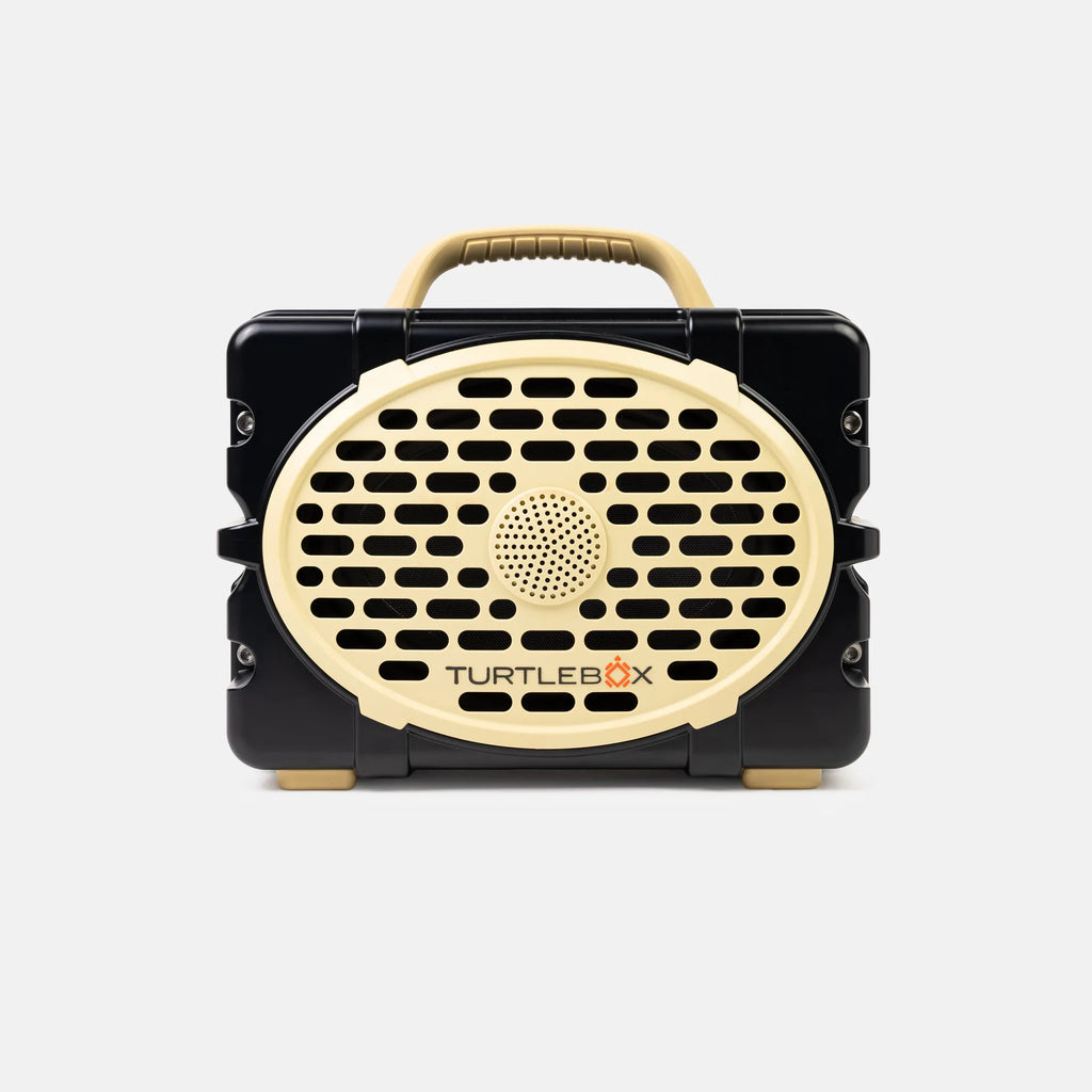 A portable Turtlebox speaker in a black and beige color scheme, shown from the front against a light gray background.