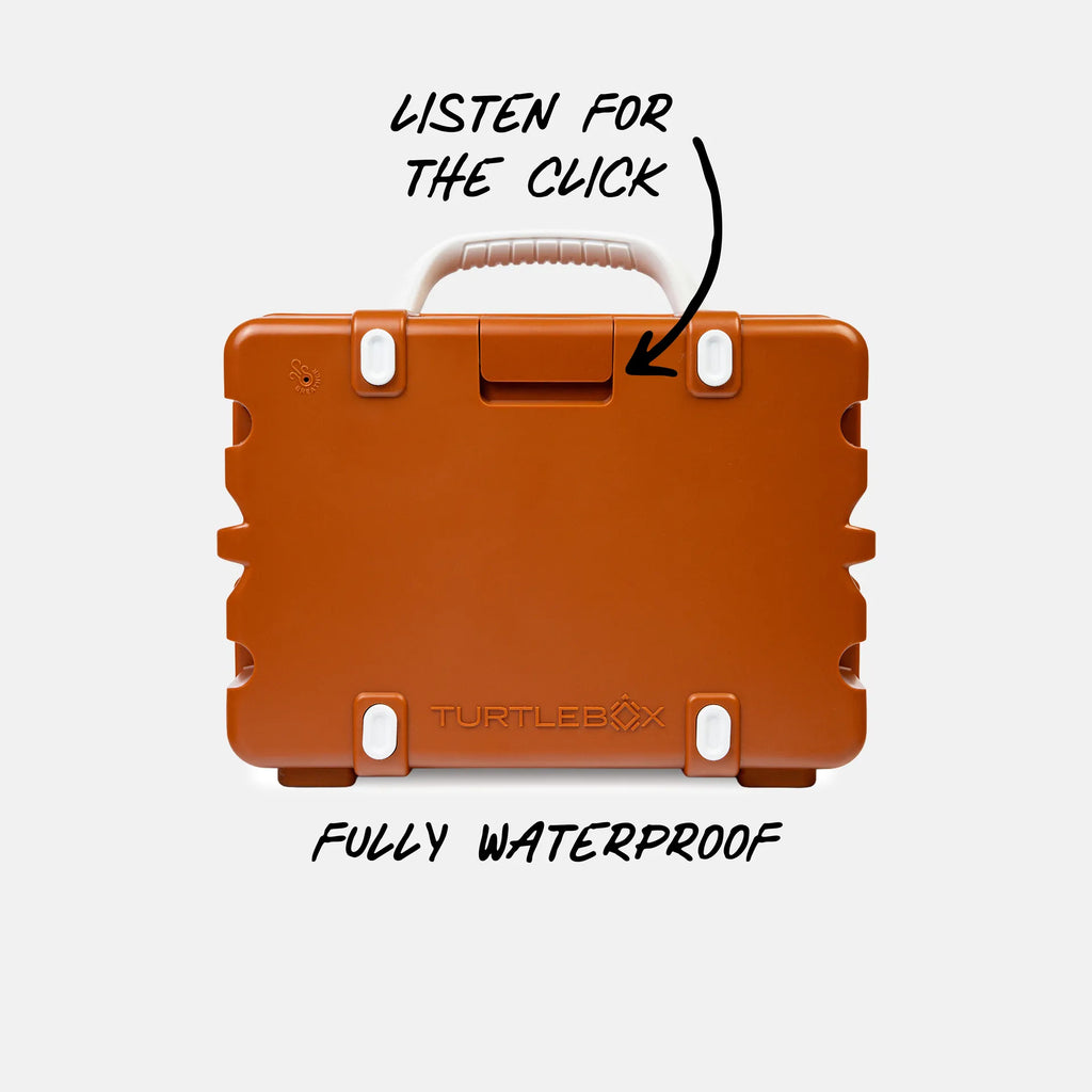 An orange waterproof hard case shown from the back on a light gray background, with handwritten text and arrows pointing to the latch and handle, plus the words 'LISTEN FOR THE CLICK' and 'FULLY WATERPROOF'. The Turtlebox brand name is embossed near the bottom.
