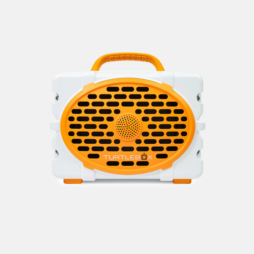 A portable Turtlebox speaker in white and bright orange, featuring a large oval front grille with the brand name printed on it, set against a clean light gray background.