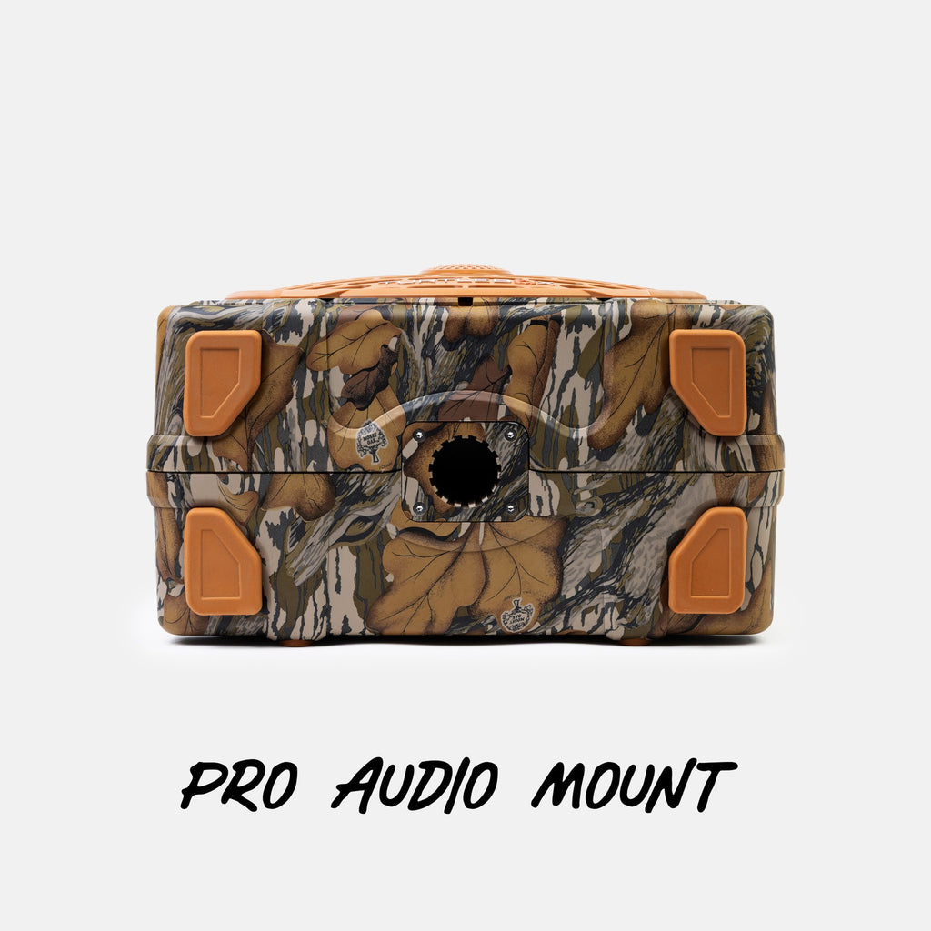 A camouflage-patterned Pro Audio Mount box with orange corner protectors and a circular cutout on the front, shown on a light gray background with the text 'PRO AUDIO MOUNT' below.