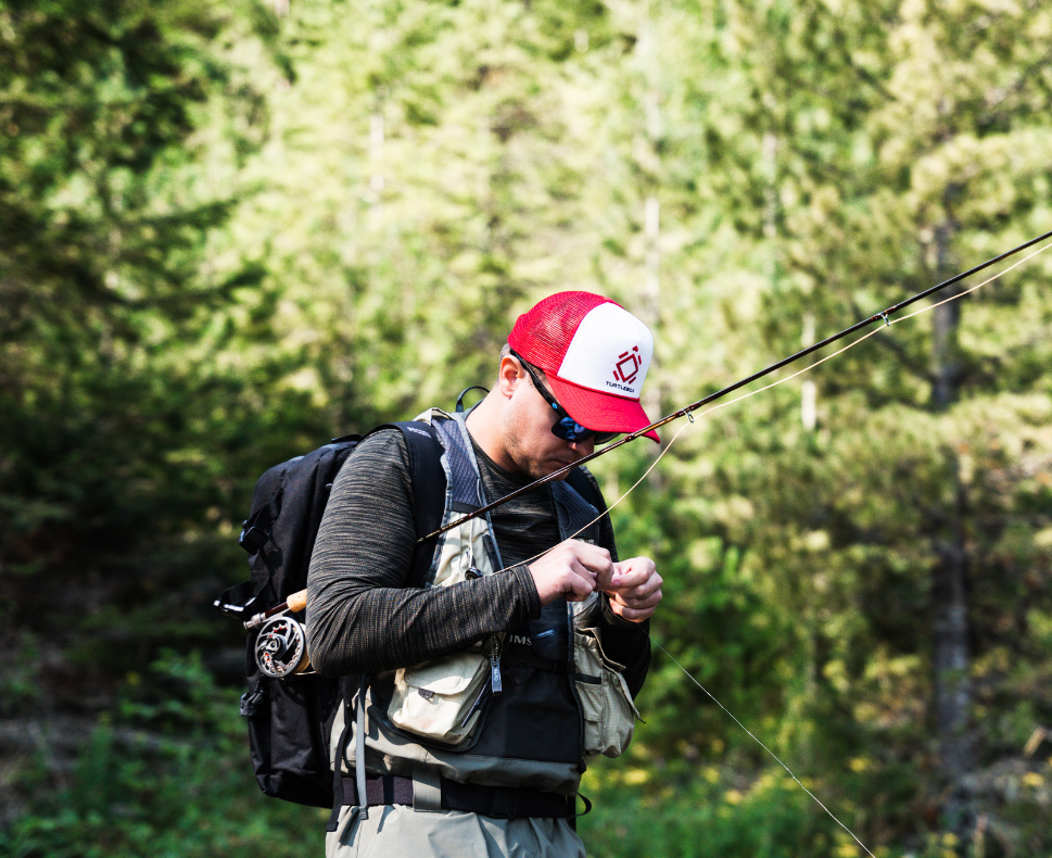Lifestyle photo of a man fishing wearing a Cotton Oxford Foam-Front Trucker cap