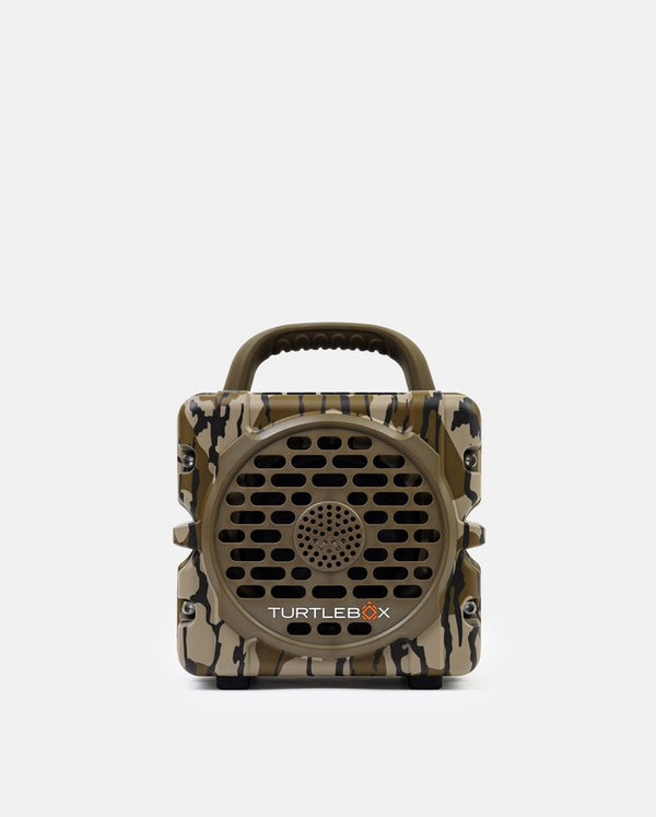 A Turtlebox portable speaker with a camouflage pattern in shades of brown, beige, and black, featuring a built-in handle and a circular speaker grille on the front.