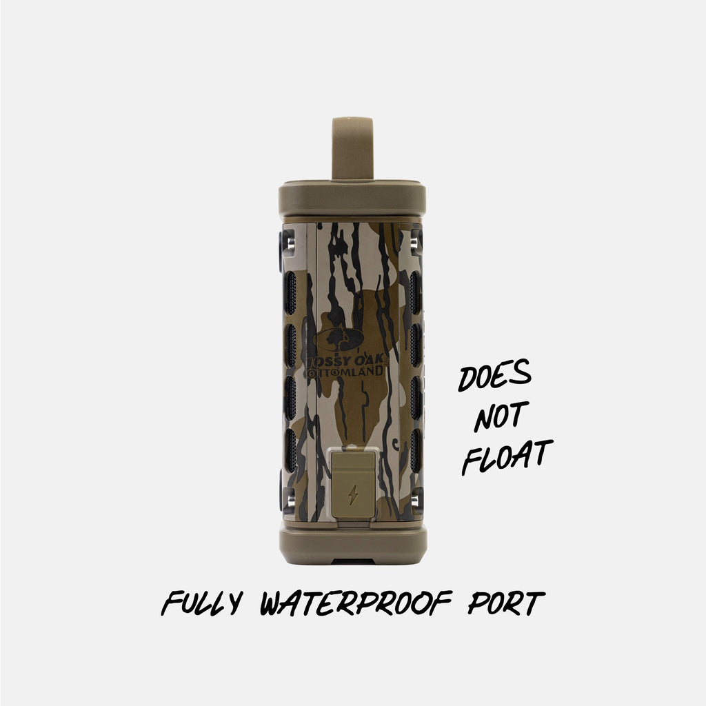 A cylindrical waterproof device with a camouflage pattern and tan top loop, shown on a light gray background with text reading 'DOES NOT FLOAT' and 'FULLY WATERPROOF PORT'.