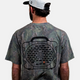 A lifestyle photo showing the back of our Mossy Oak Full Foliage Tee on a man wearing a hat.