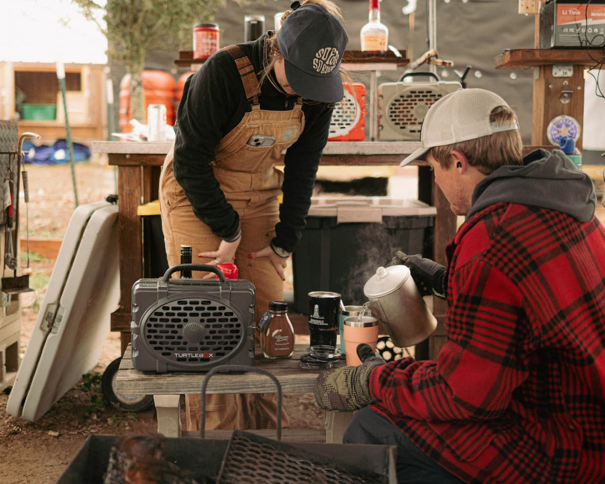 A lifestyle photo of a couple pouring boiling water to make tea and the Turtlebox Original speaker is playing music over the table. #speaker-color_gray