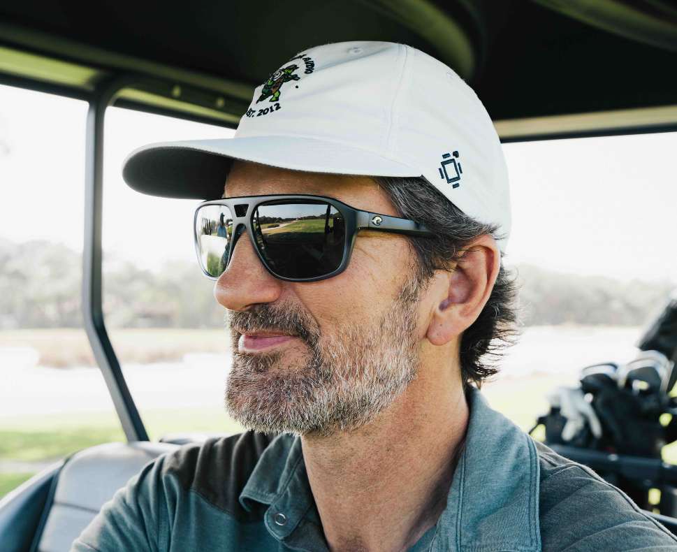 A lifestyle photo of a man with sunglasses wearing the Turtlebox Golfin Turtle Hat