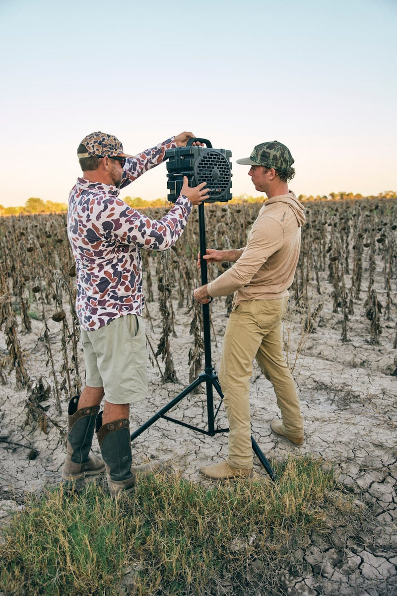 A lifestyle photo of two founders mounting a Grande speaker in gray on an audio mount.
