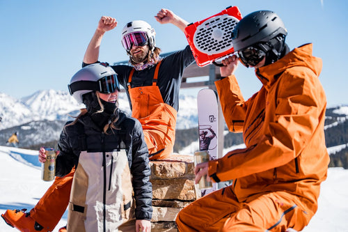 A lifestyle photo of three freeskiers listening music from a Original Gen 3 Orange speaker