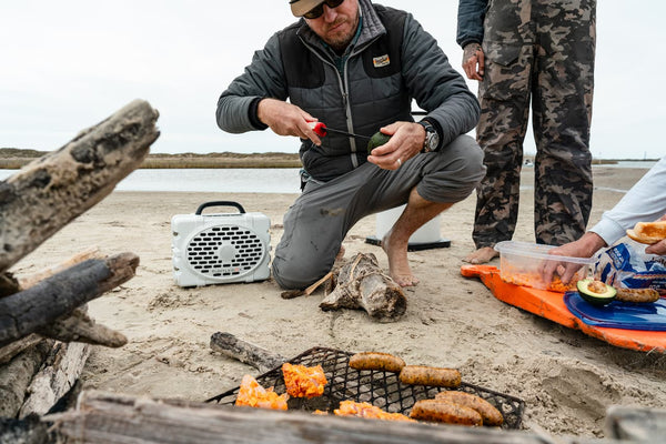 A lifestyle photo of a guy preparing an avocado with some meat in a grill.