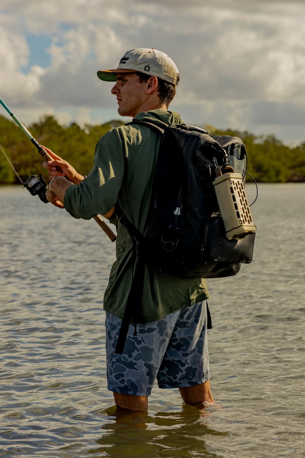 lifestyle photo showing a man fishing, with a Tan Ranger speaker attached to his backpack #base-color_tan