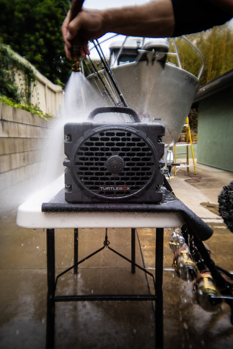 A lifestyle photo of a man washing his Turtlebox Grande speaker in gray color #speaker-color_gray