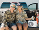 Lifestyle photo of a couple and a dog sitting on the back of a truck with a white turtlebox. The woman is wearing a Live Free Patch Blue Hat