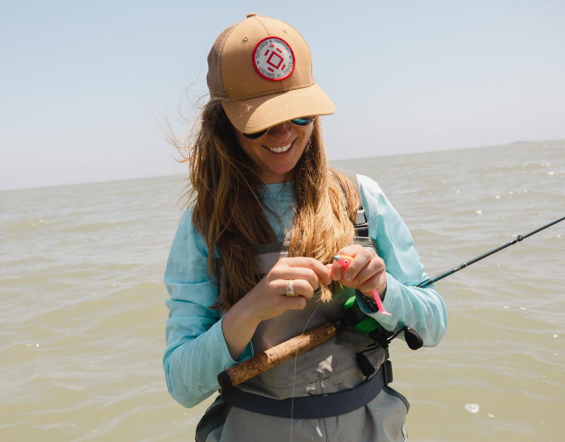 Lifestyle photo of a woman fishing, wearing an Original Tan Patch Hat