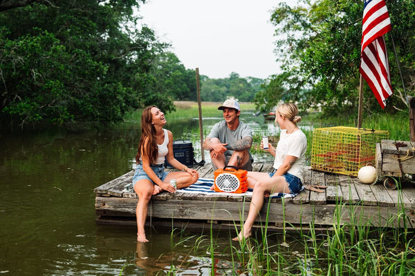 A group of friend sitted in a deck drinking and listening music from Original speaker