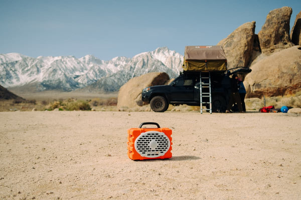 A Original speaker on the sand with a jeep behind