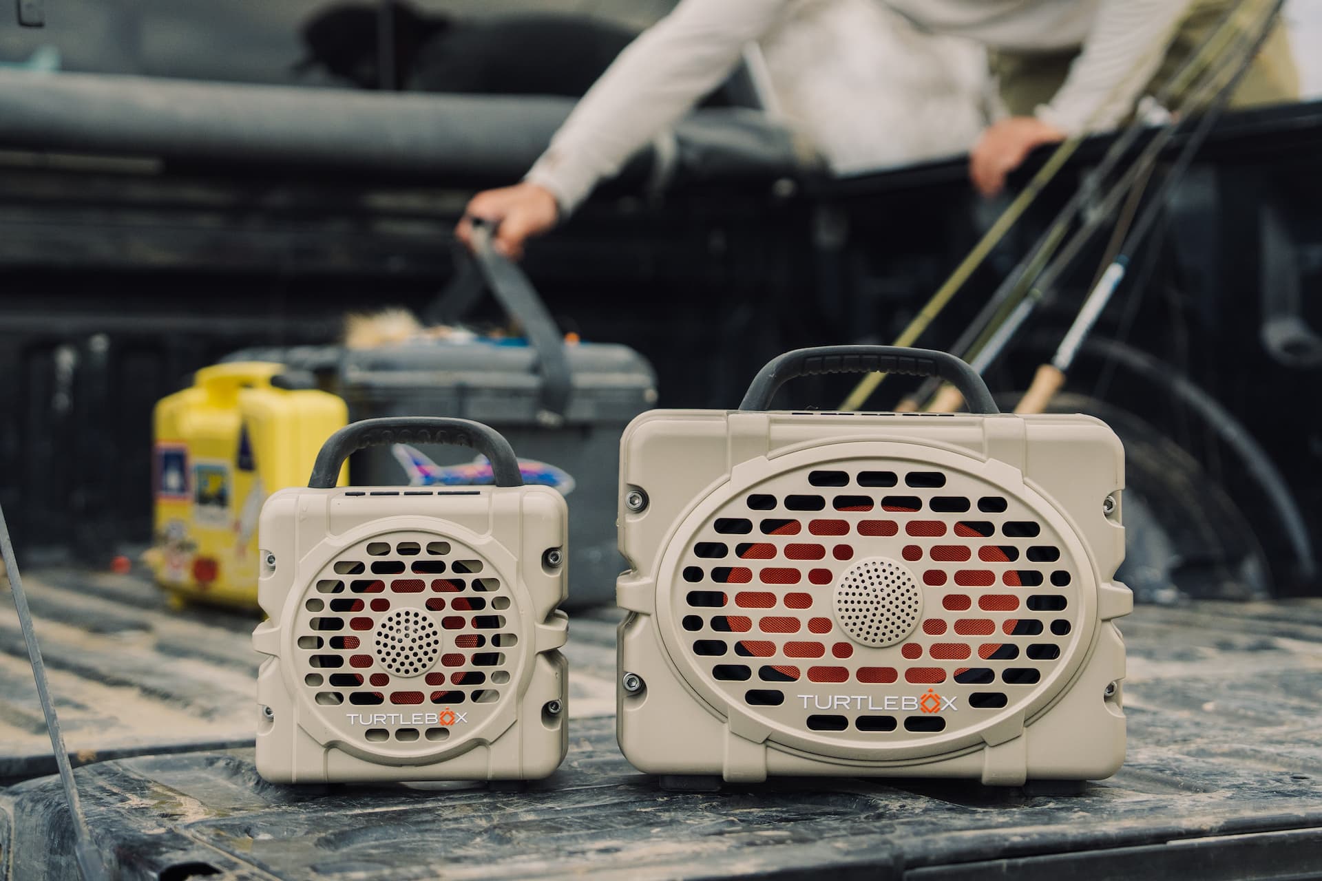 Two portable speakers on a truck bed with a blurred background