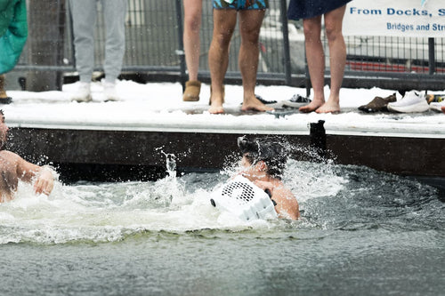 Person swimming in a pool with spectators watching from the side