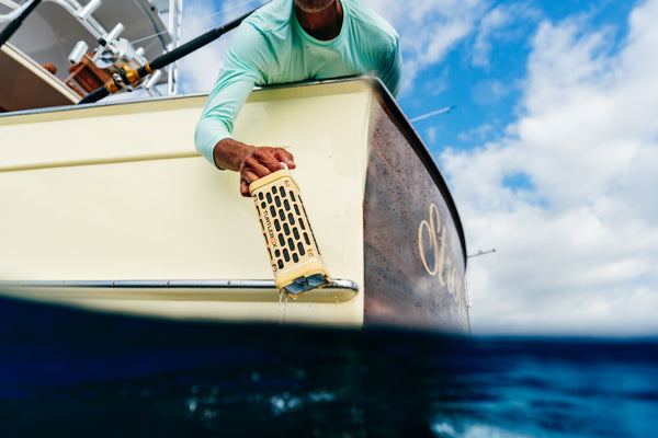 Person on a boat holding a fishing lure with a scenic ocean background
