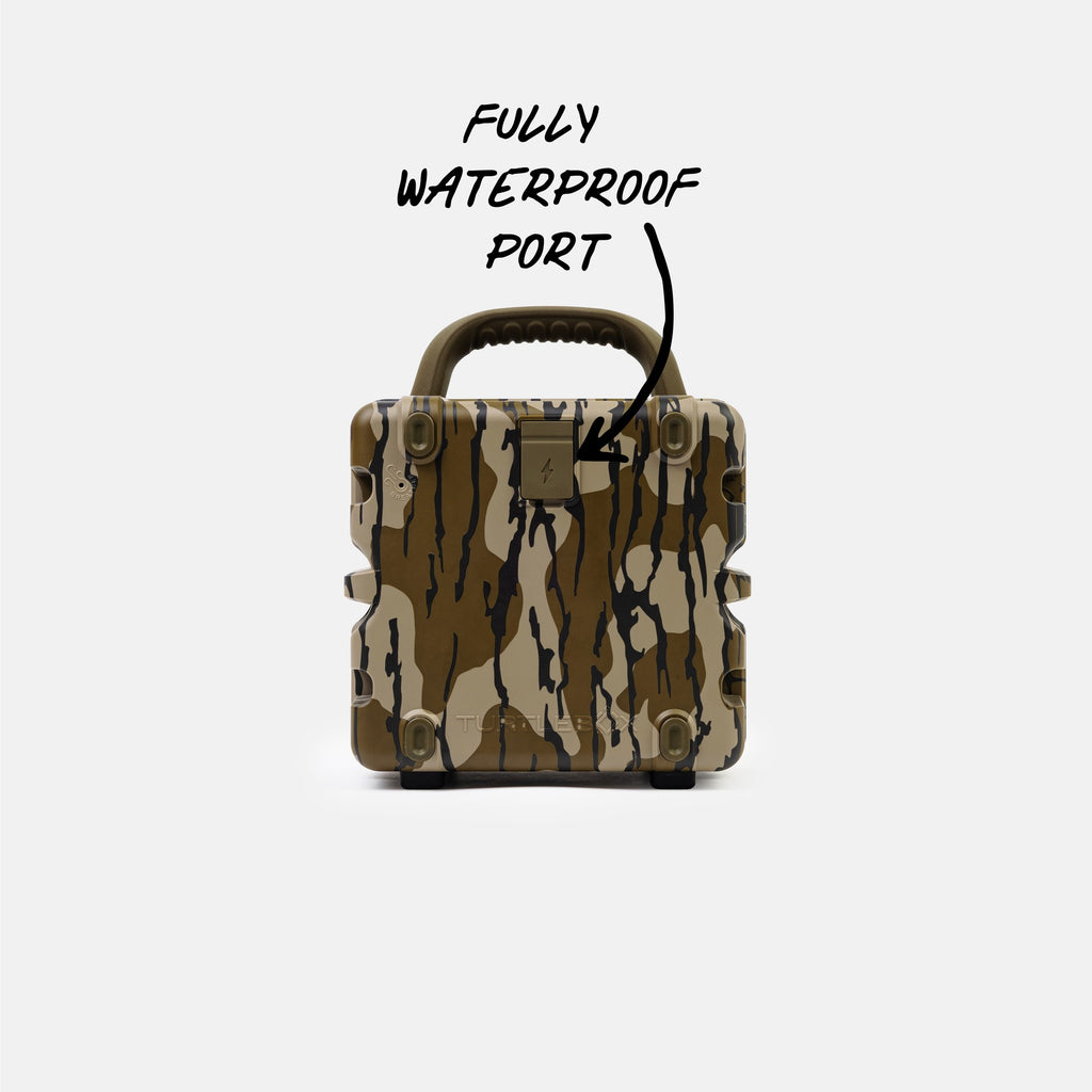 A rugged hard-shell case with a brown, beige, and black camouflage pattern, featuring a top handle and a metal port cover. Handwritten text above reads 'FULLY WATERPROOF PORT' with an arrow pointing to the metal port on the front.