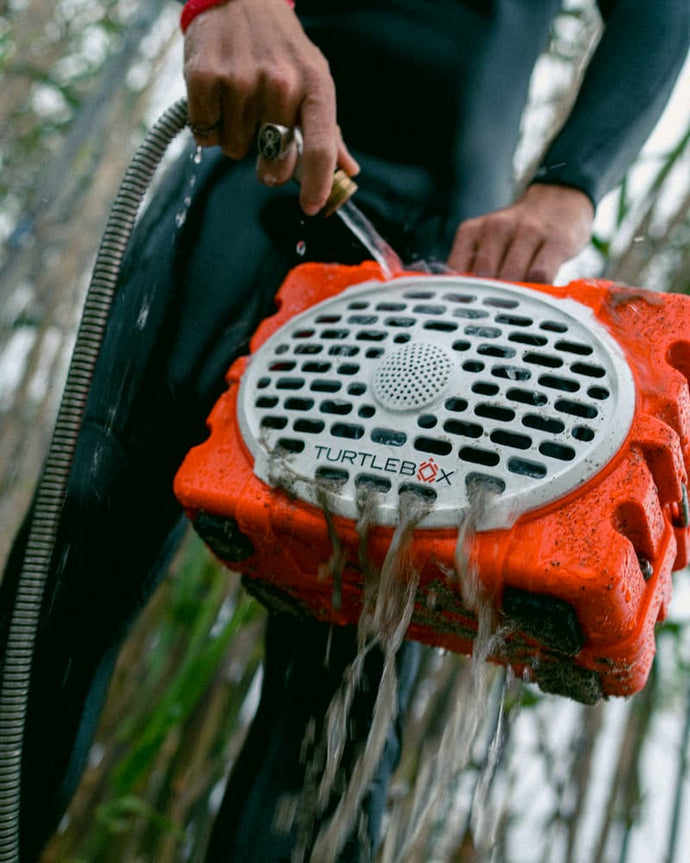 Person using a Original Orange Turtlebox shower head outdoors