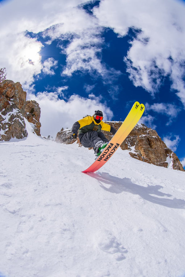 Person snowboarding down a snowy slope with a colorful snowboard and mountainous background.