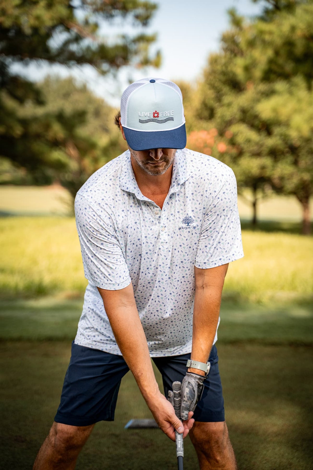 lifestyle man playing golf wearing live free wave hat