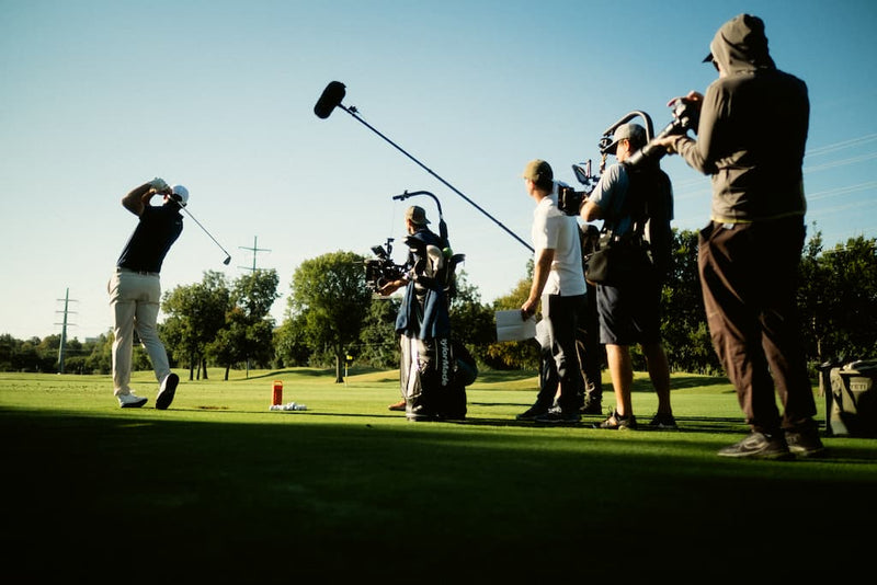 Scottie Scheffler in action with camera crew on a golf course