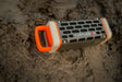 A lifestyle photo of a Turtlebox Delta Ranger speaker on a sandy mud surface #base-color_delta
