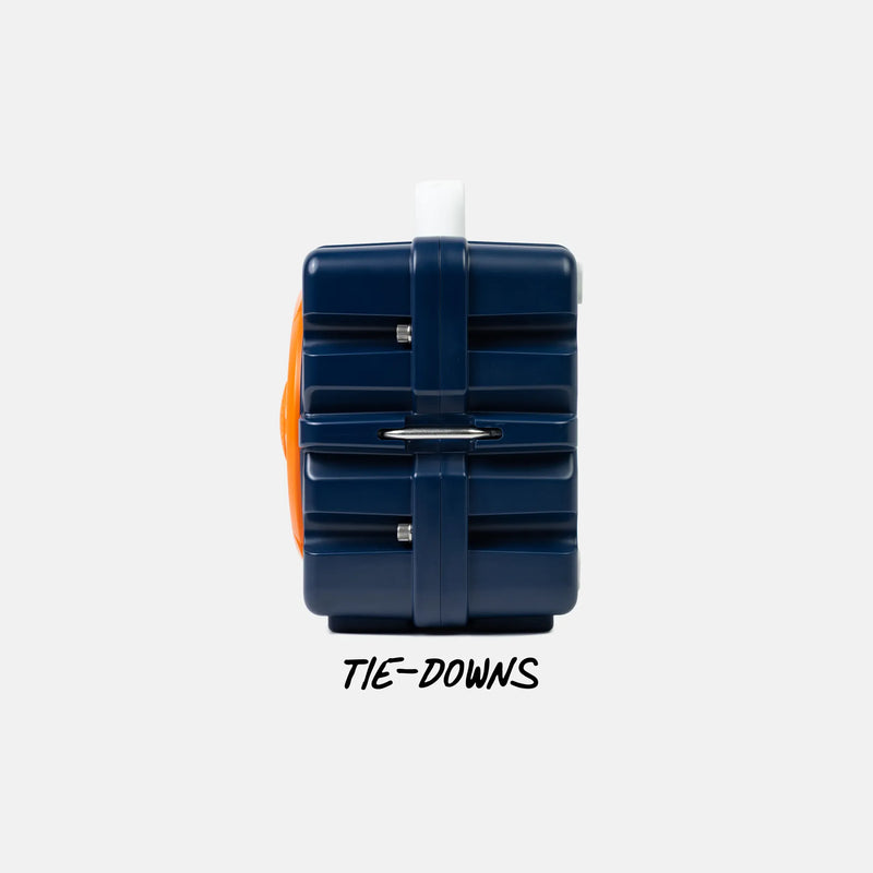A navy blue hard-sided luggage-style case with a white handle and orange side accent, shown on a light gray background with the text 'TIE-DOWNS' below.