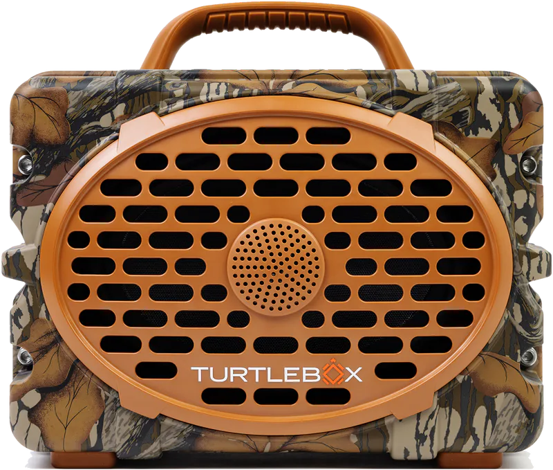 A portable Turtlebox speaker with a camouflage pattern body, a prominent orange-brown oval speaker grille, and a matching handle on top, shown against a plain white background.