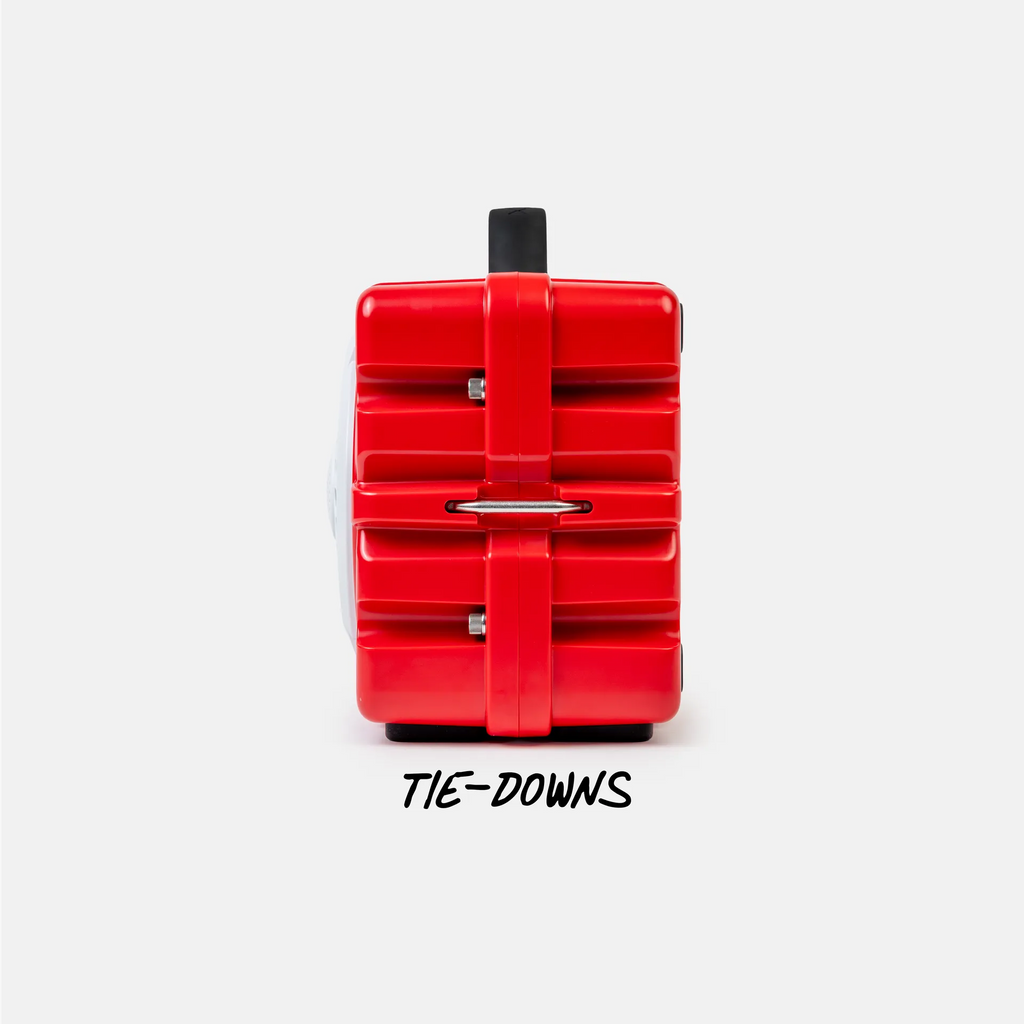 A bright red hard-shell suitcase shown from the back on a light gray background, with a black handle and the word 'TIE-DOWNS' printed below.