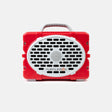A red portable speaker by TurtleBox with a white oval front grille, black speaker holes, a gray carrying handle, and small gray feet, shown on a light gray background.
