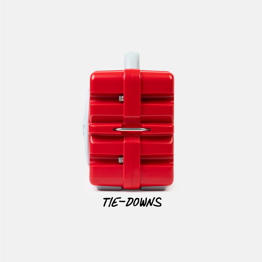 A red plastic tie-down strap or restraint accessory with a white plastic end, shown from the side against a light gray background, with the text 'TIE-DOWNS' printed below.