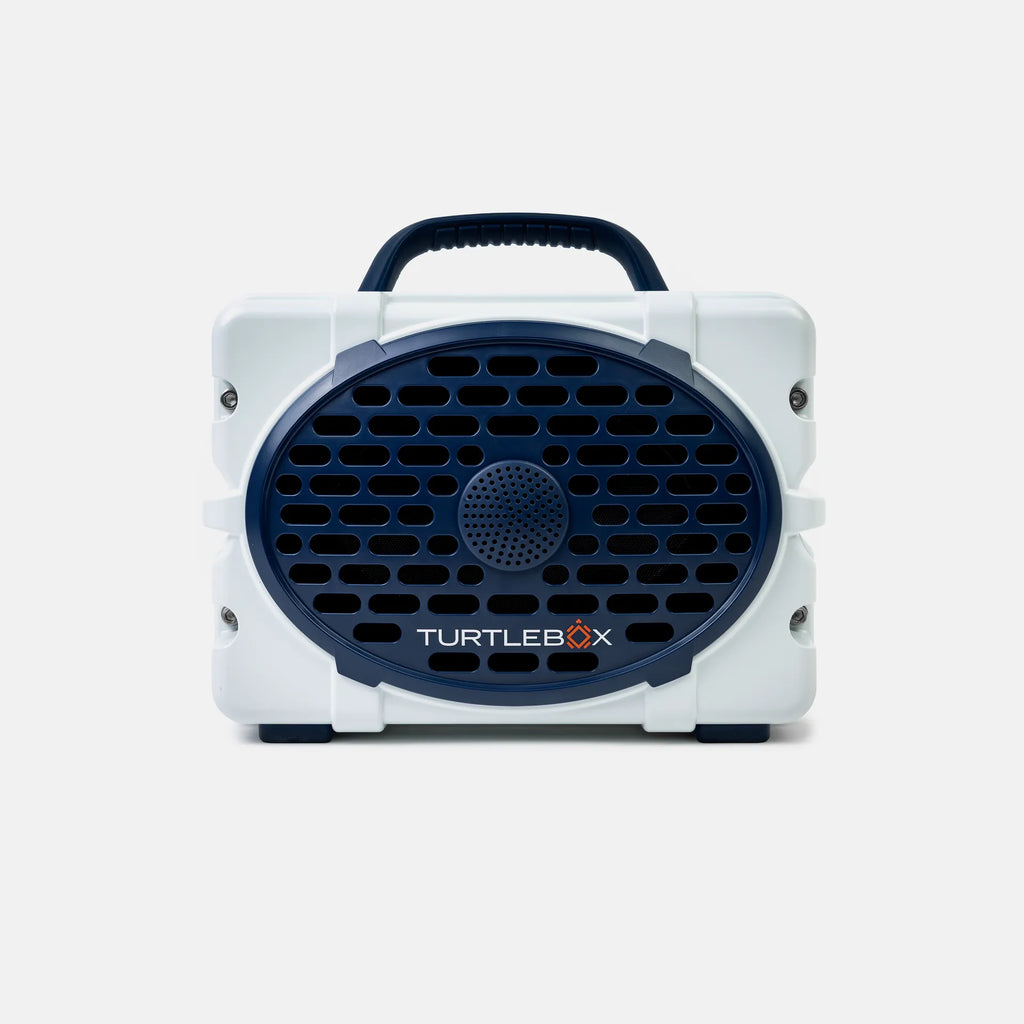 A white and navy blue portable speaker by Turtlebox, featuring a circular front grille with the brand name printed on it, set against a light gray background.