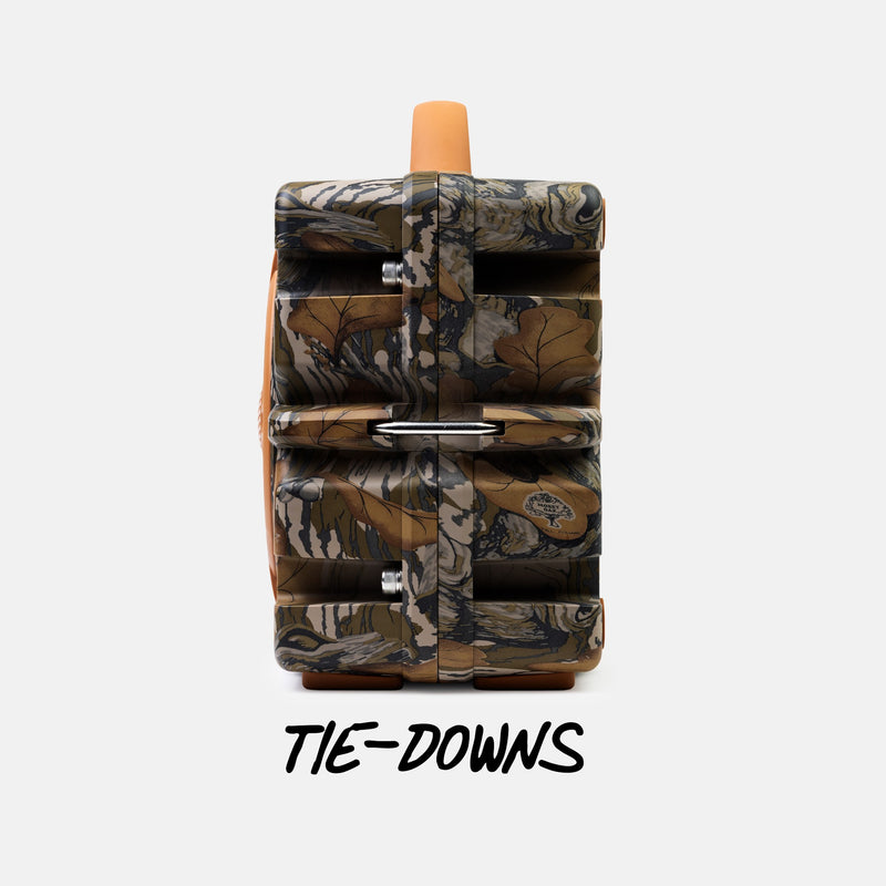 A camouflage-patterned multi-tiered storage container or organizer with a top handle and metal clips, shown on a light gray background with the text 'TIE-DOWNS' below.