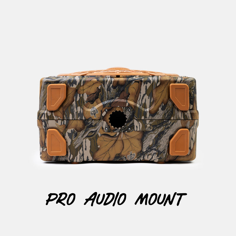 A camouflage-patterned Pro Audio Mount box with orange corner protectors and a circular cutout on the front, shown on a light gray background with the text 'PRO AUDIO MOUNT' below.
