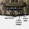 Close-up of the top control panel of a Turtlebox portable speaker with a Mossy Oak Bottomland camouflage pattern, featuring hand-drawn callouts for Bluetooth, 2-Box Stereo Pairing, and Party Mode.