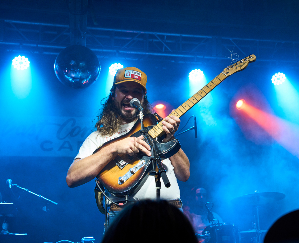 Lifestyle photo of a man playing the guitar and singing in a concert, wearing the Cowboy Carpenter Hat