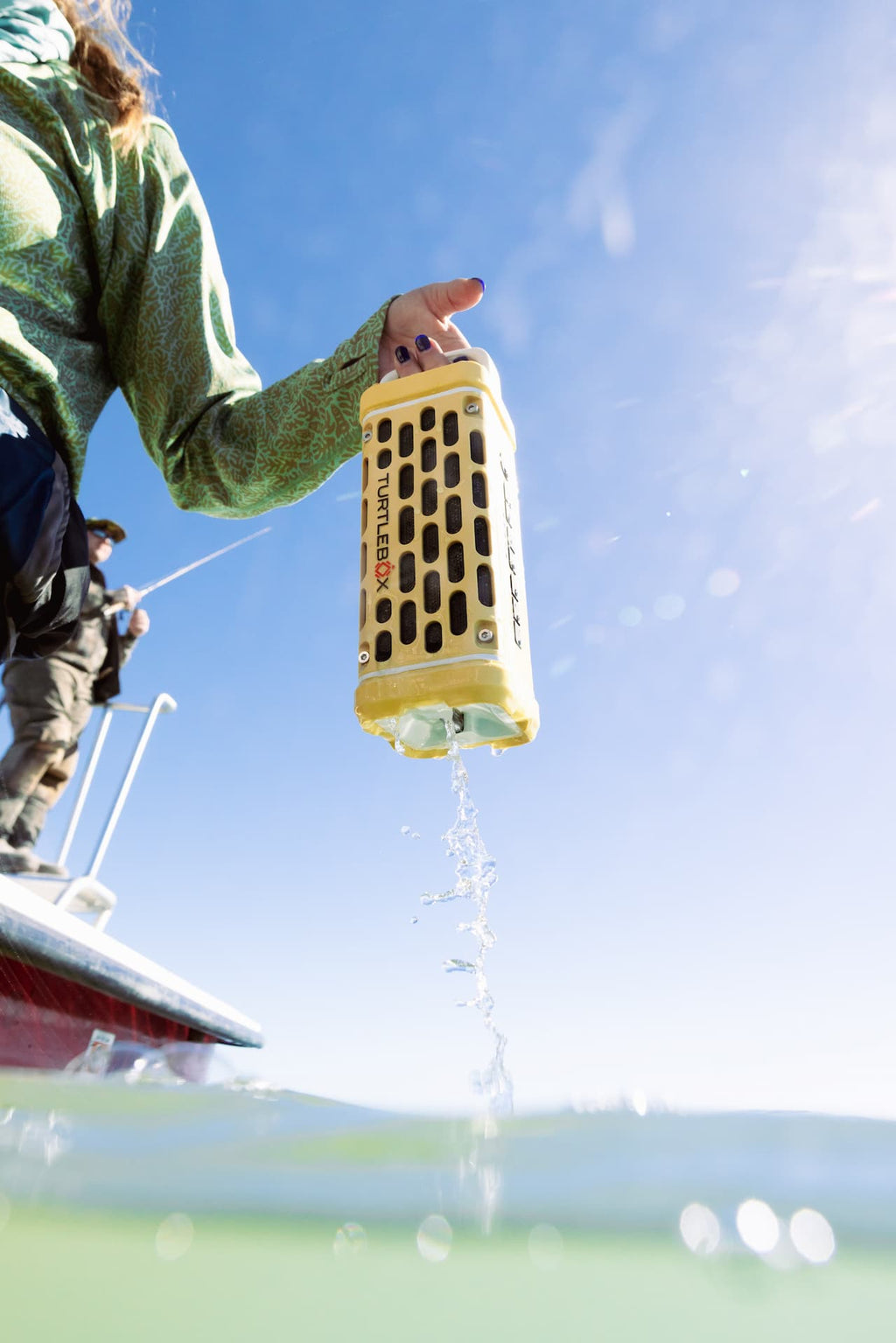 A lifestyle photo from a person holding a yellow and black device over water with a clear blue sky in the background #base-color_fighting-lady-yellow
