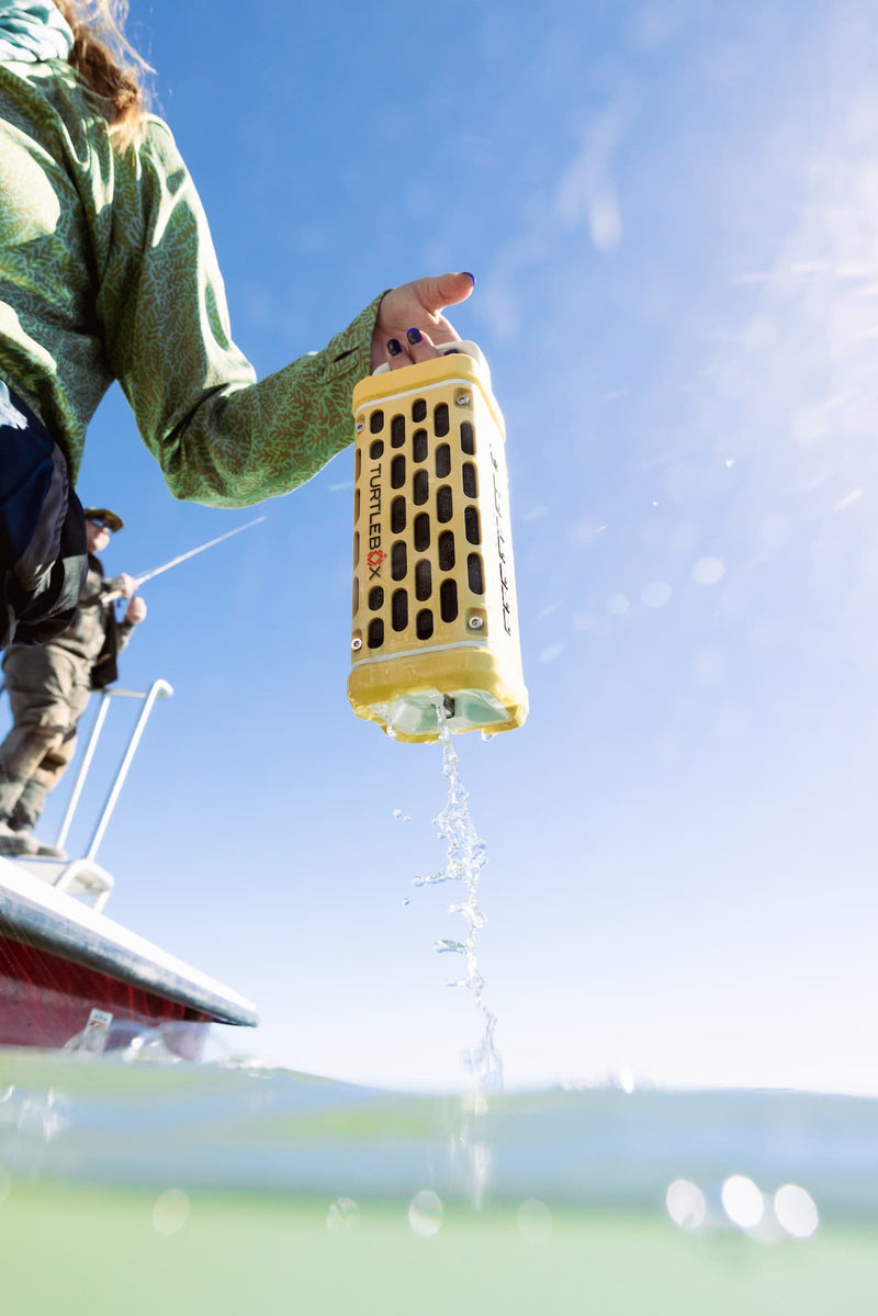 A lifestyle photo from a person holding a yellow and black device over water with a clear blue sky in the background #base-color_fighting-lady-yellow