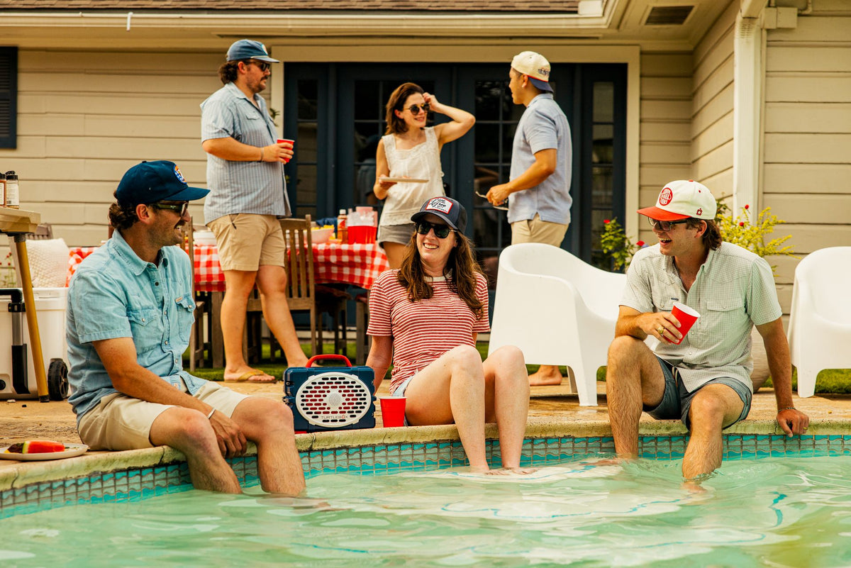Group of people by a poolside with a table and chairs in the background