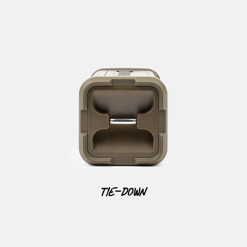 A top-down view of a square outdoor storage container lid in a muted olive-tan color, featuring a central tie-down loop and the text 'TIE-DOWN' printed below on a light gray background.