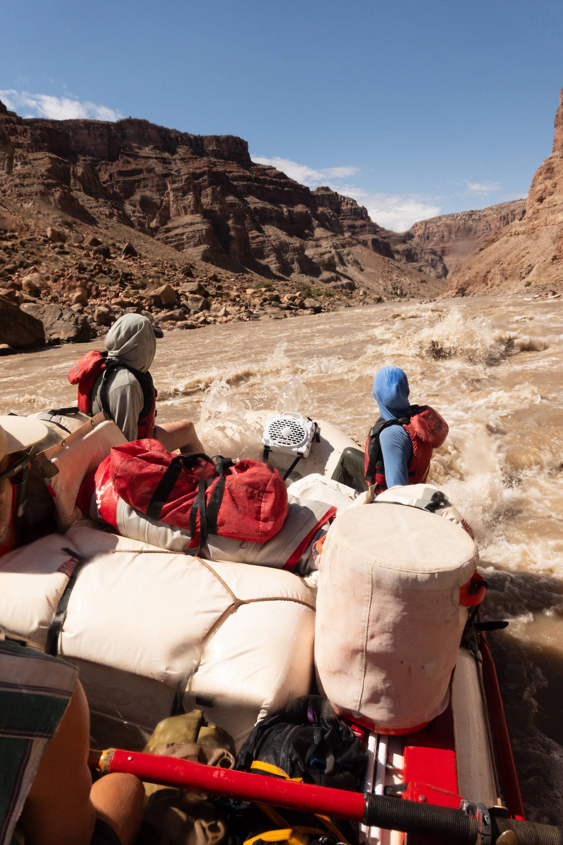People and stuff in a raft with an Original White speaker going down the river
