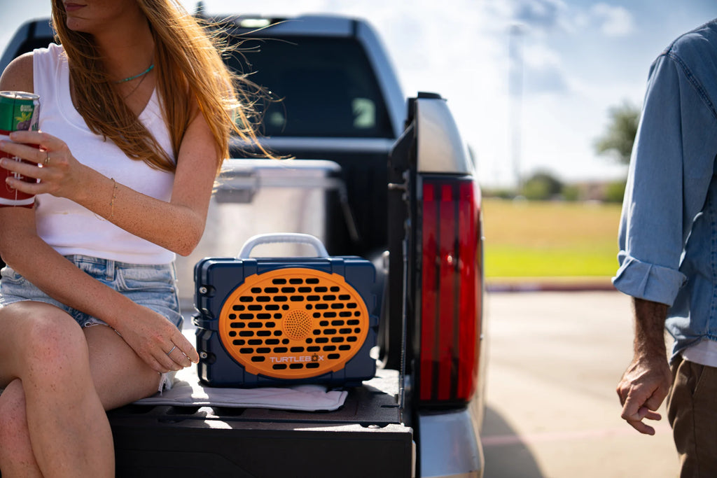 A lifestyle photo of a Navy & Orange Original Gen 3 speaker. #speaker-color_navy-orange-gameday-series