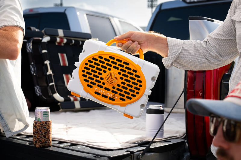 A lifestyle photo of a White & Orange Original Gen 3 speaker. #speaker-color_white-orange-gameday-series