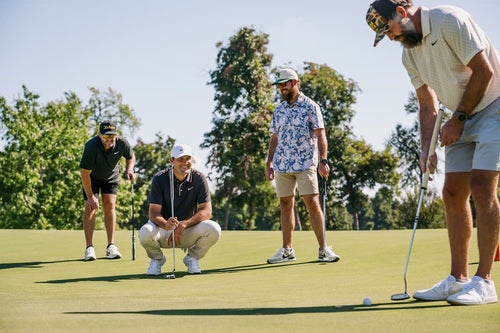 Four Turtlebox founders playing golf on a green course with trees in the background