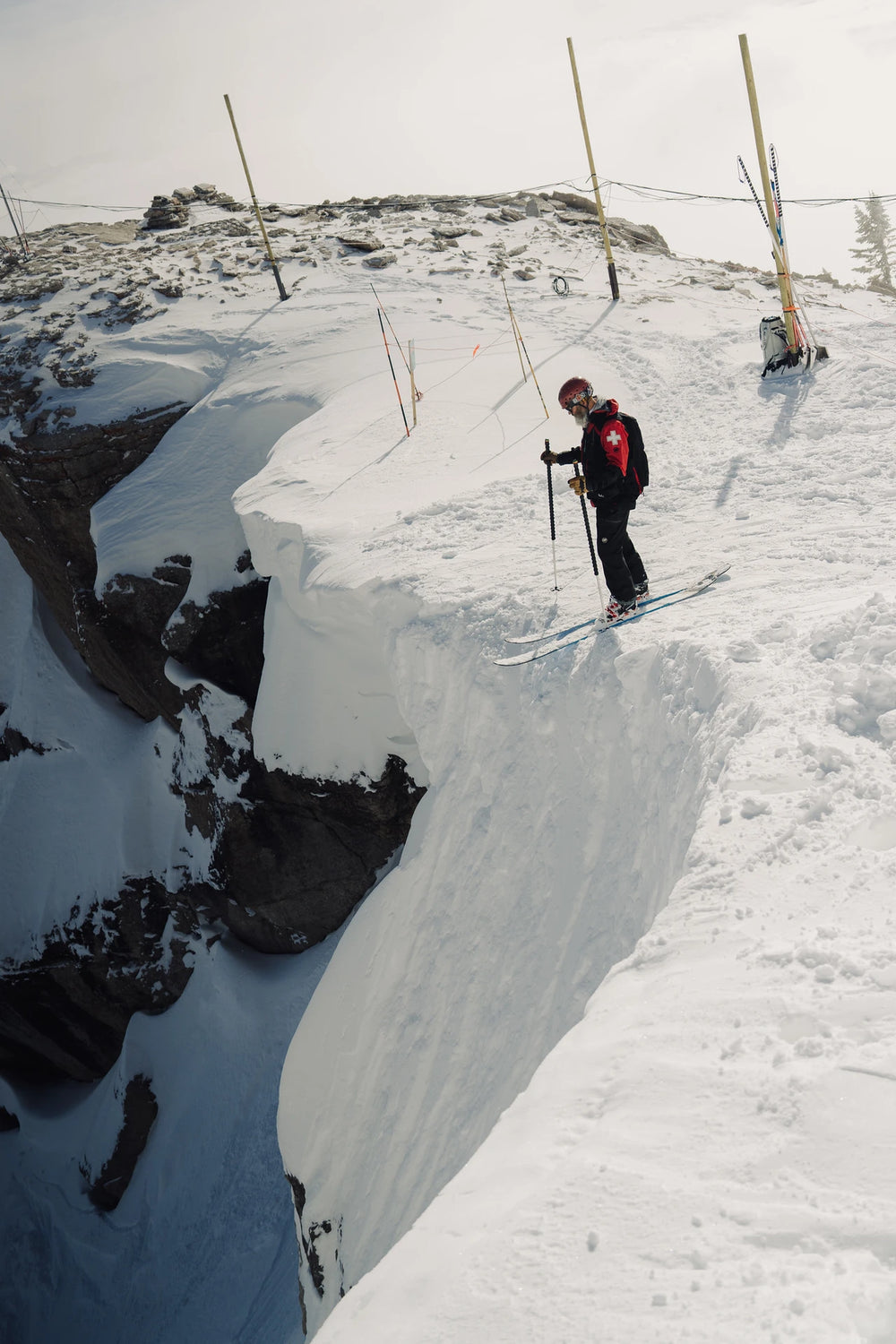 Person on skis standing on a snowy ledge with a crevasse below