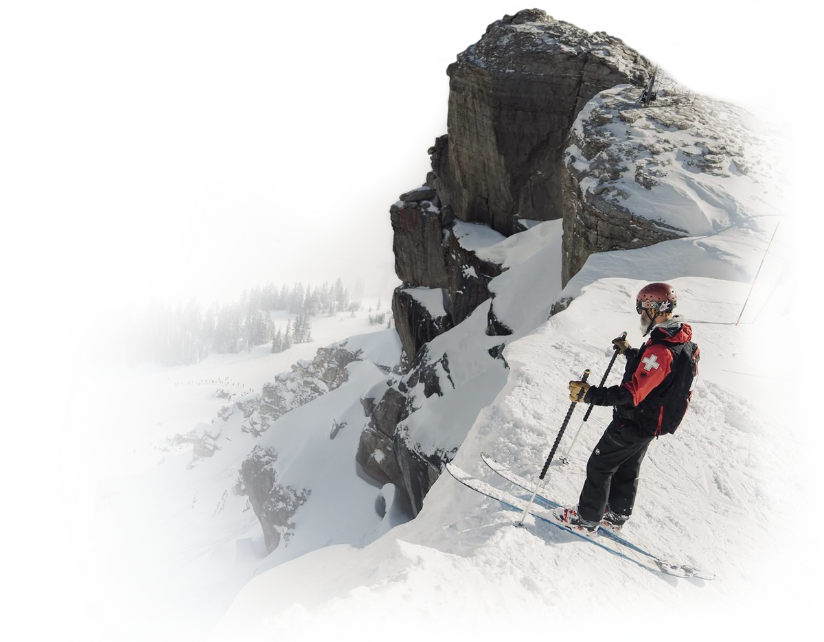 Person skiing on a snowy mountain with rocky cliffs in the background