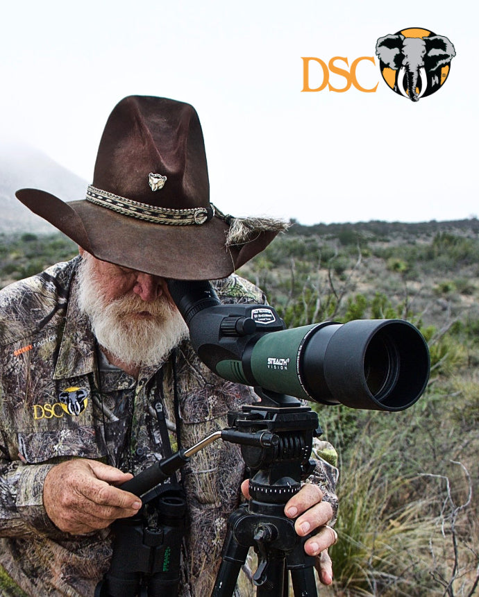 Man in camouflage clothing and cowboy hat using a spotting scope with DSC logo in the corner.